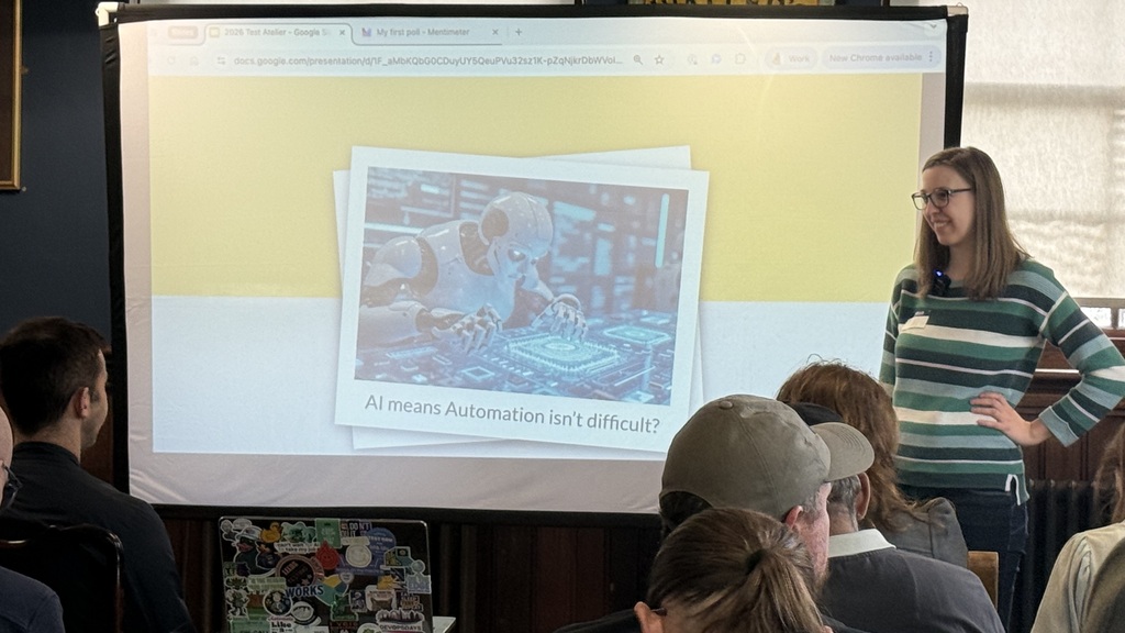 Emily stands at the front of a slide with a robot and the caption, AI means that automation isn’t difficult. She is w... image