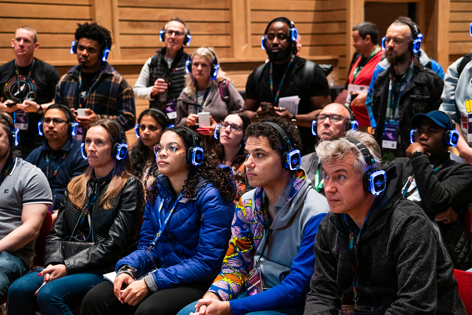 A small crowd of people with headphones listening to Postman people talking.