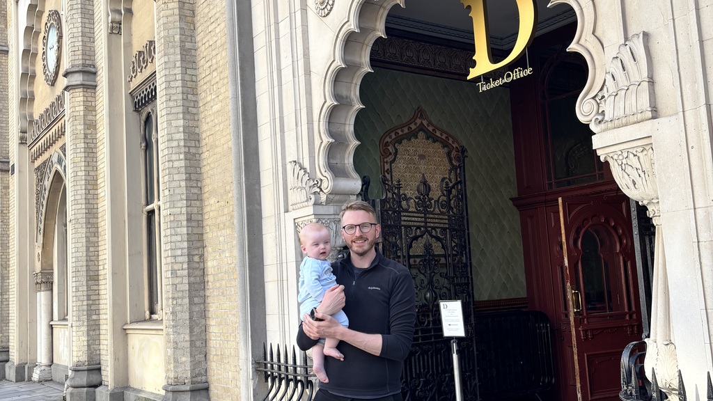 Adam holding Harris outside the entrance to Brighton Dome, with the venue’s name above them. image