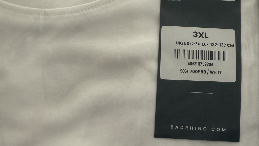 White T-shirt in clear packaging. A tag says 3xl, a sticker says 3xl, the T-shirt on the back inside the collar says 2xl 