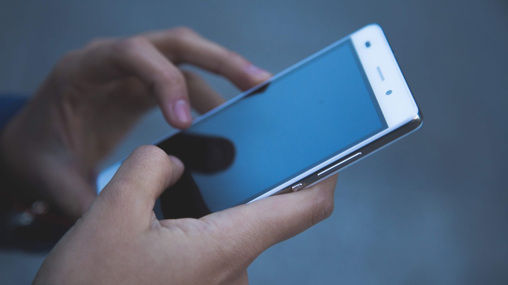 A close up of a person holding a mobile phone tapping at the screen  image