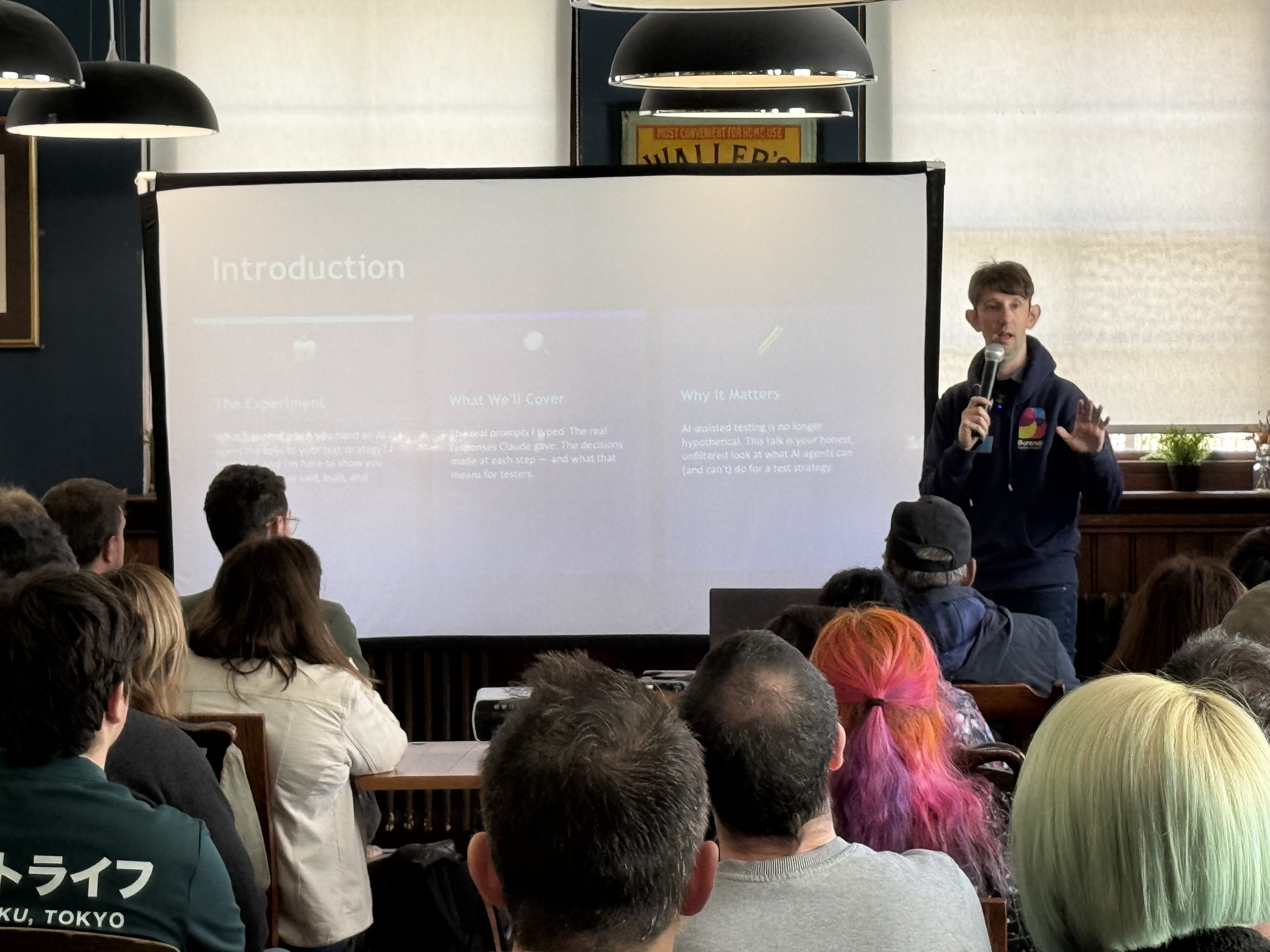 Chris stands at the front of his introduction slide with a packed room watching  image