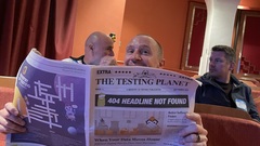 A photo of Simon Rigler sitting in the audience at TestBash Brighton holding up the newspaper "pretending" to read. 😃 image