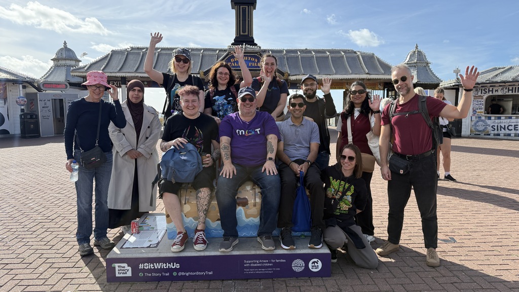A group of people in front of a pier. The sky is blue with wispy clouds. image