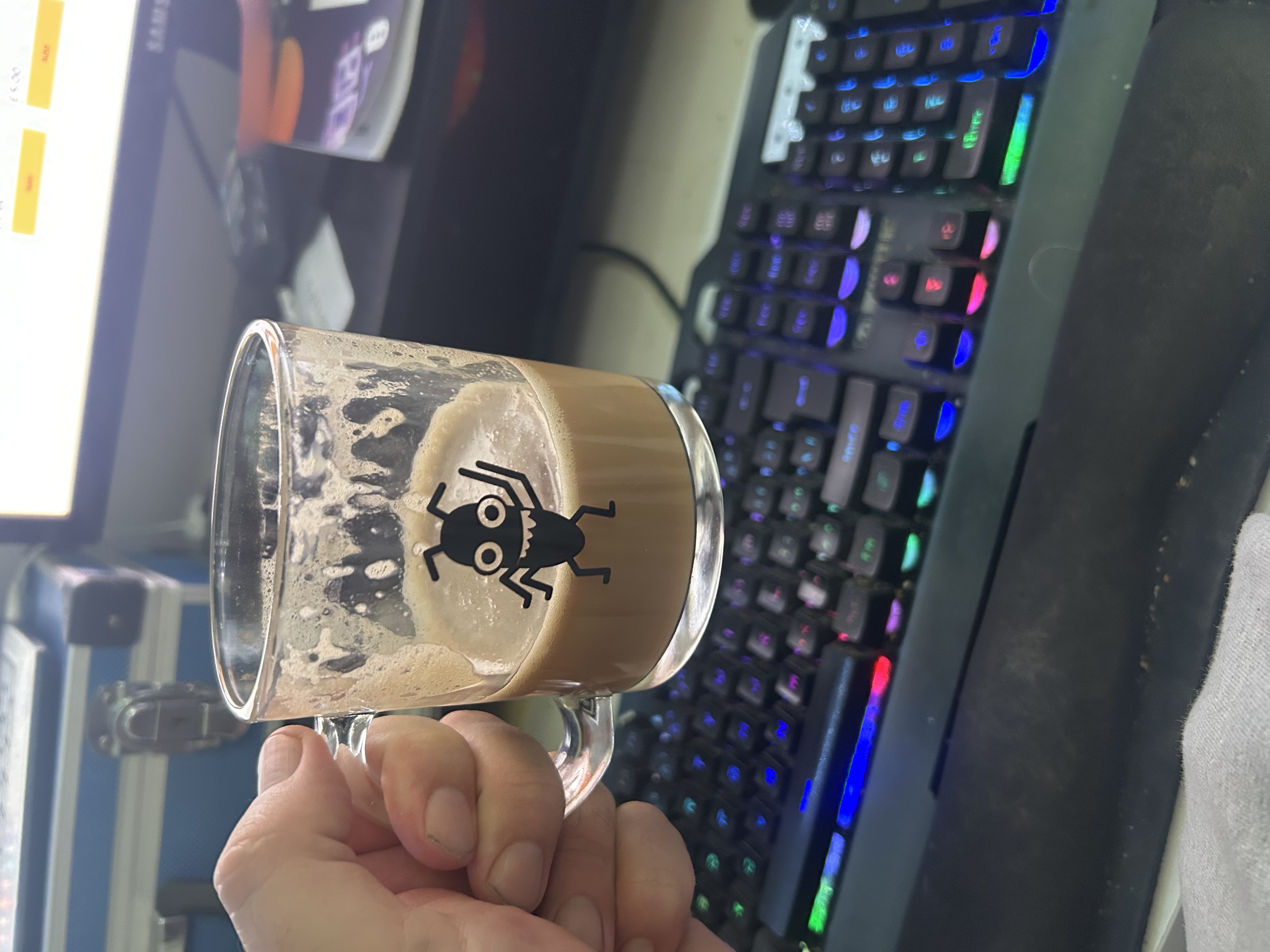 Picture of a hand with a glass mug with a bug on it 