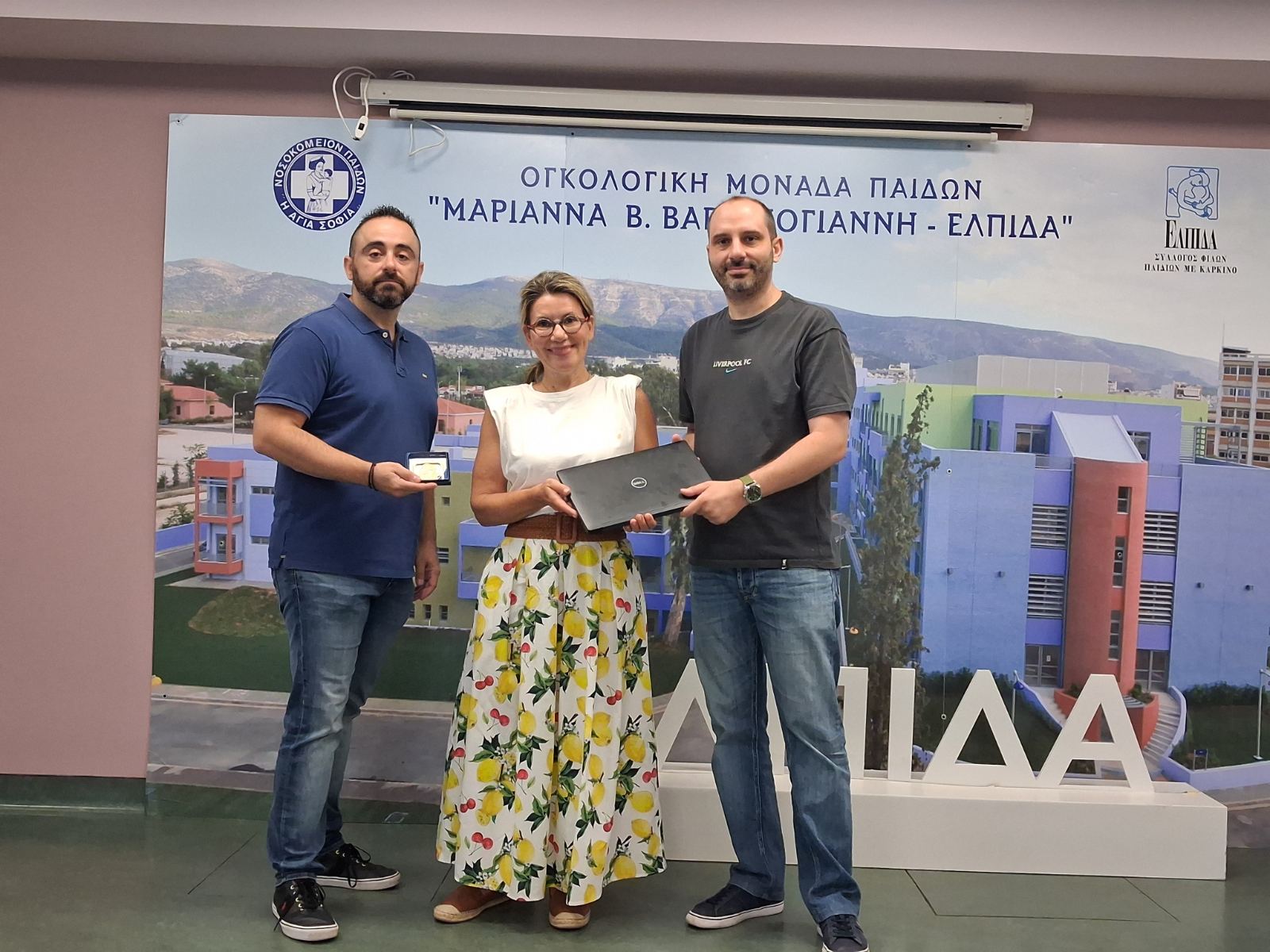 Petros and Giorgos are handing the laptops over to the Foundation's representative. image