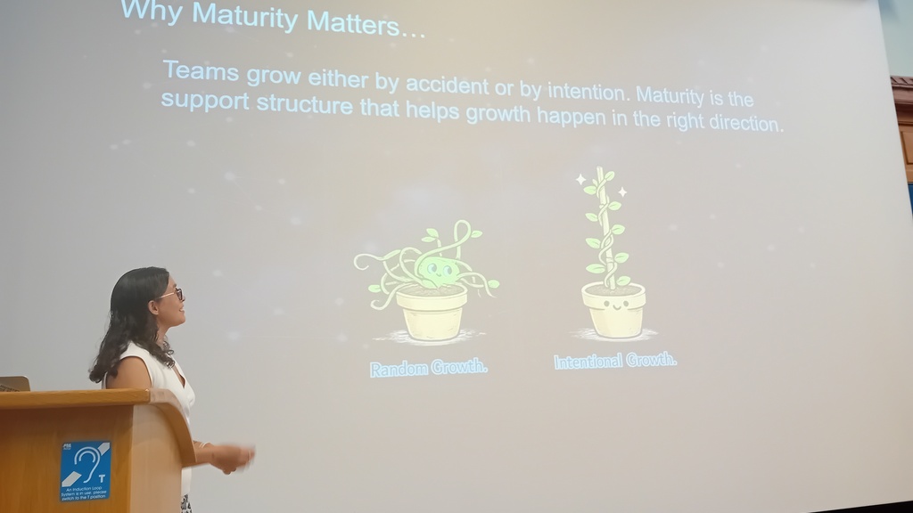 A woman standing in front of a screen presenting.  image