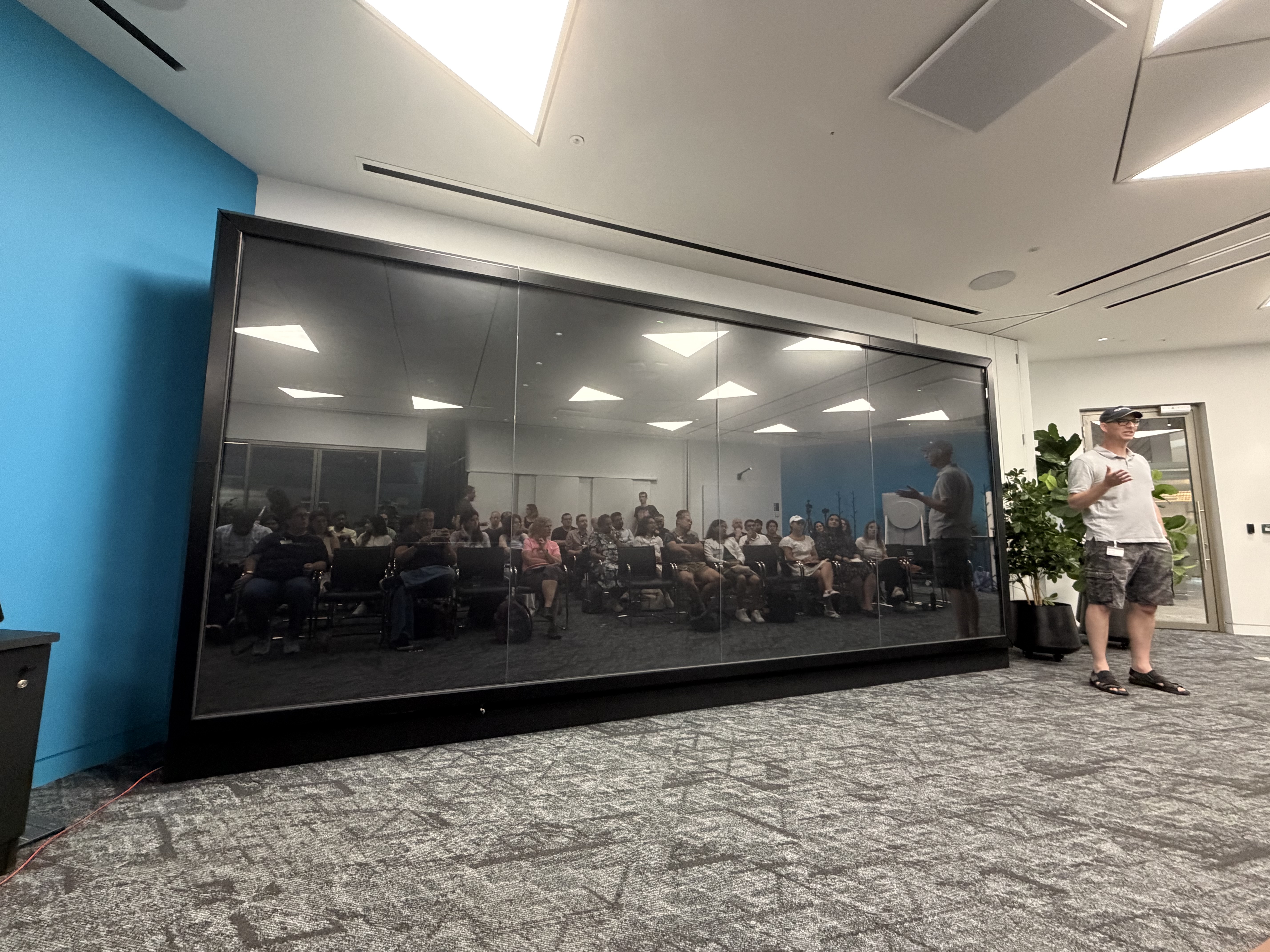 The audience of leading with AI reflected on a big presentation screen. image
