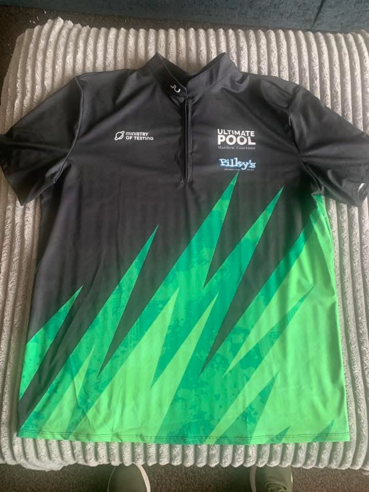 Sports shirt in black with green spikes across the lower half. The Ministry of Testing planet logo is on show. 