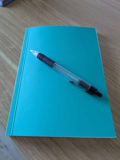 A photo of a turquoise notebook with a pen on top of the notebook. image