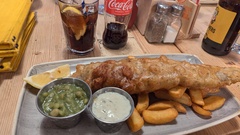 Plate of food, bettered fish, peas, with a coke in the background image