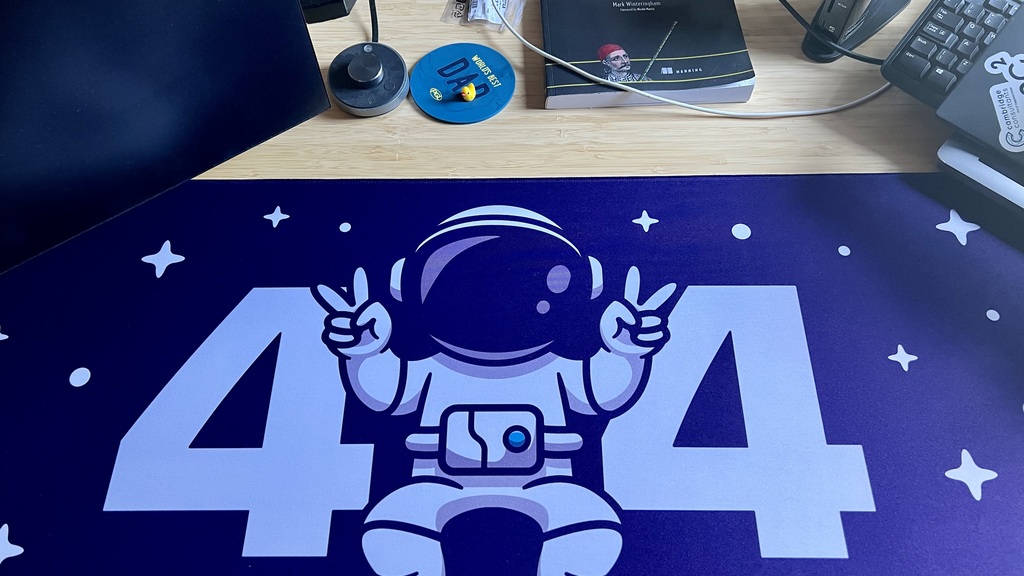 A purple desk mat with 404 written in white. The zero is represents by a cartoon style astronaut. 
