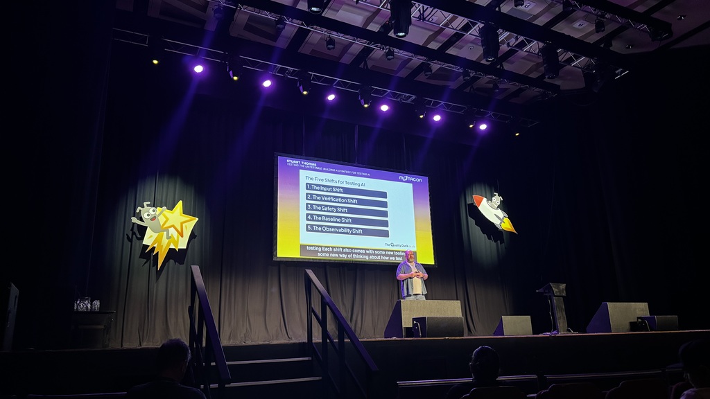 Stuart presenting “The Five Shifts for Testing AI” onstage under purple lighting.
1. The Input Shift
2. The Verific... image