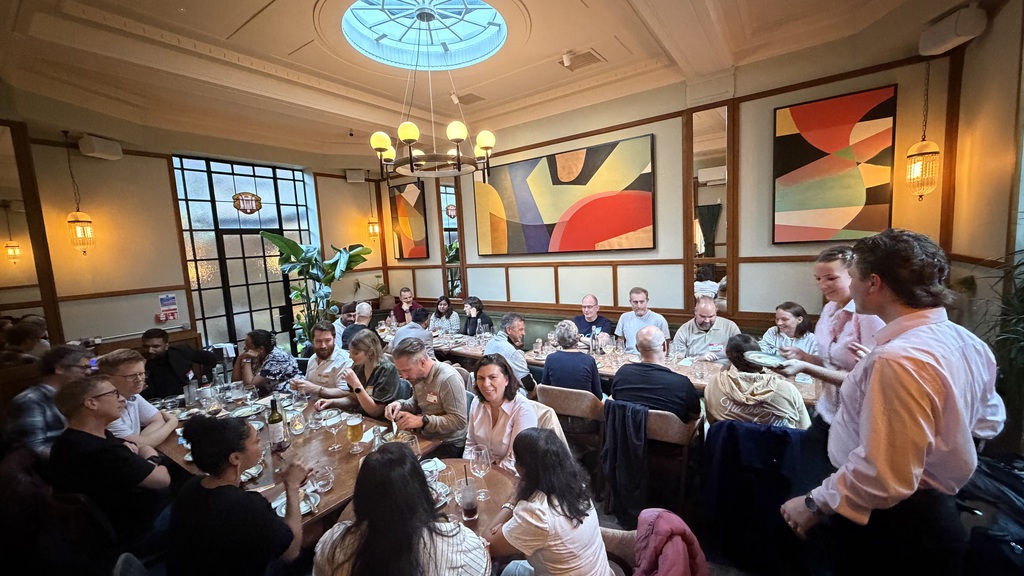 A photo of 30 people busy chatting and enjoying dinner. image