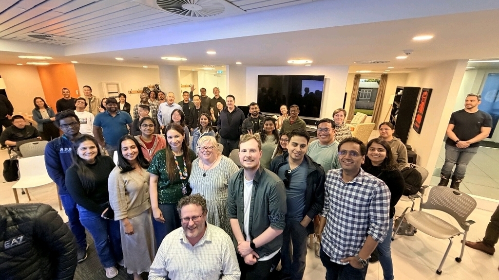 A room with 60+ attendees smiling at the camera. 