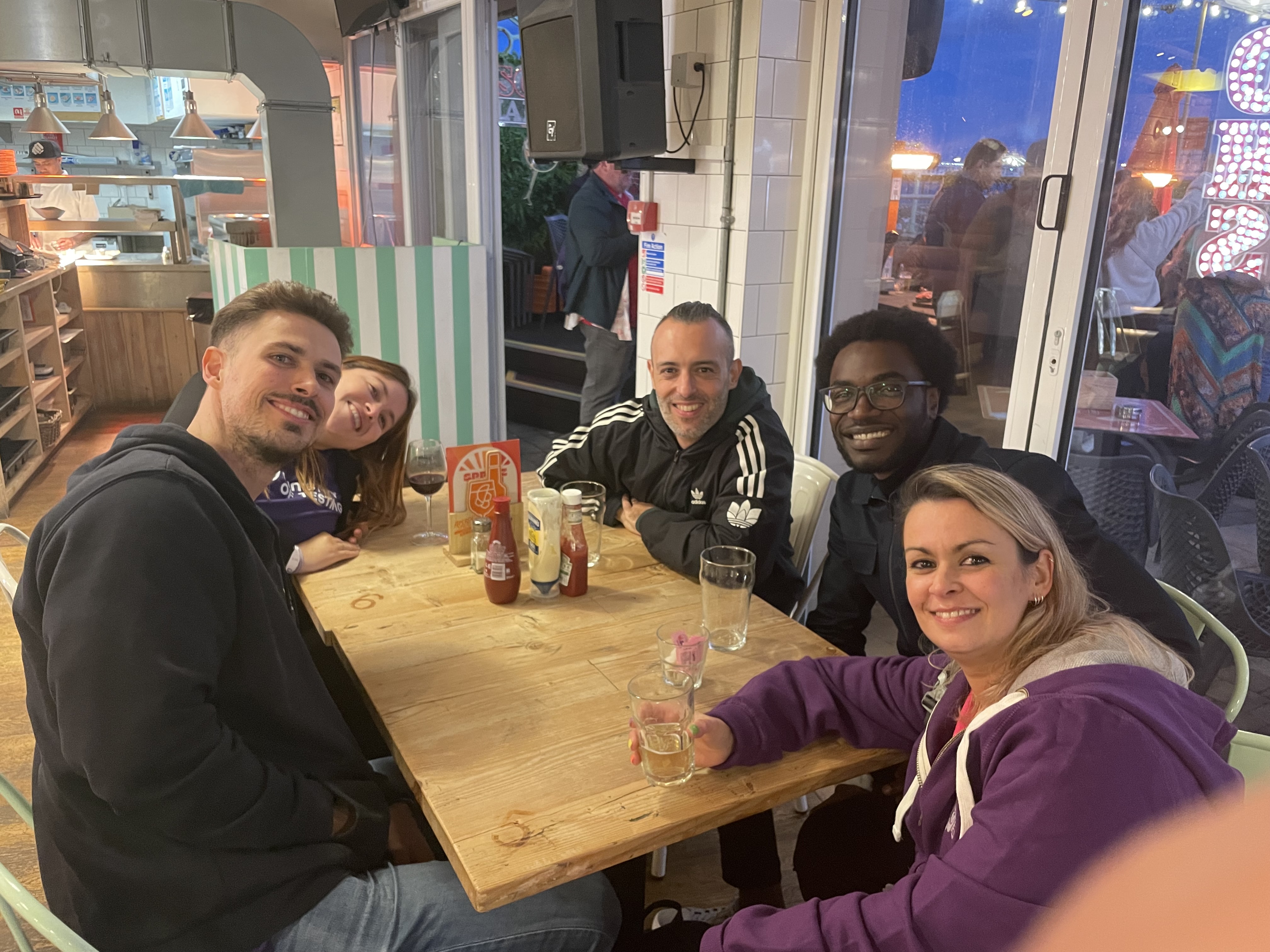 4 testers and Diana Dromey sitting around a table with drinks at the post TestBash social
