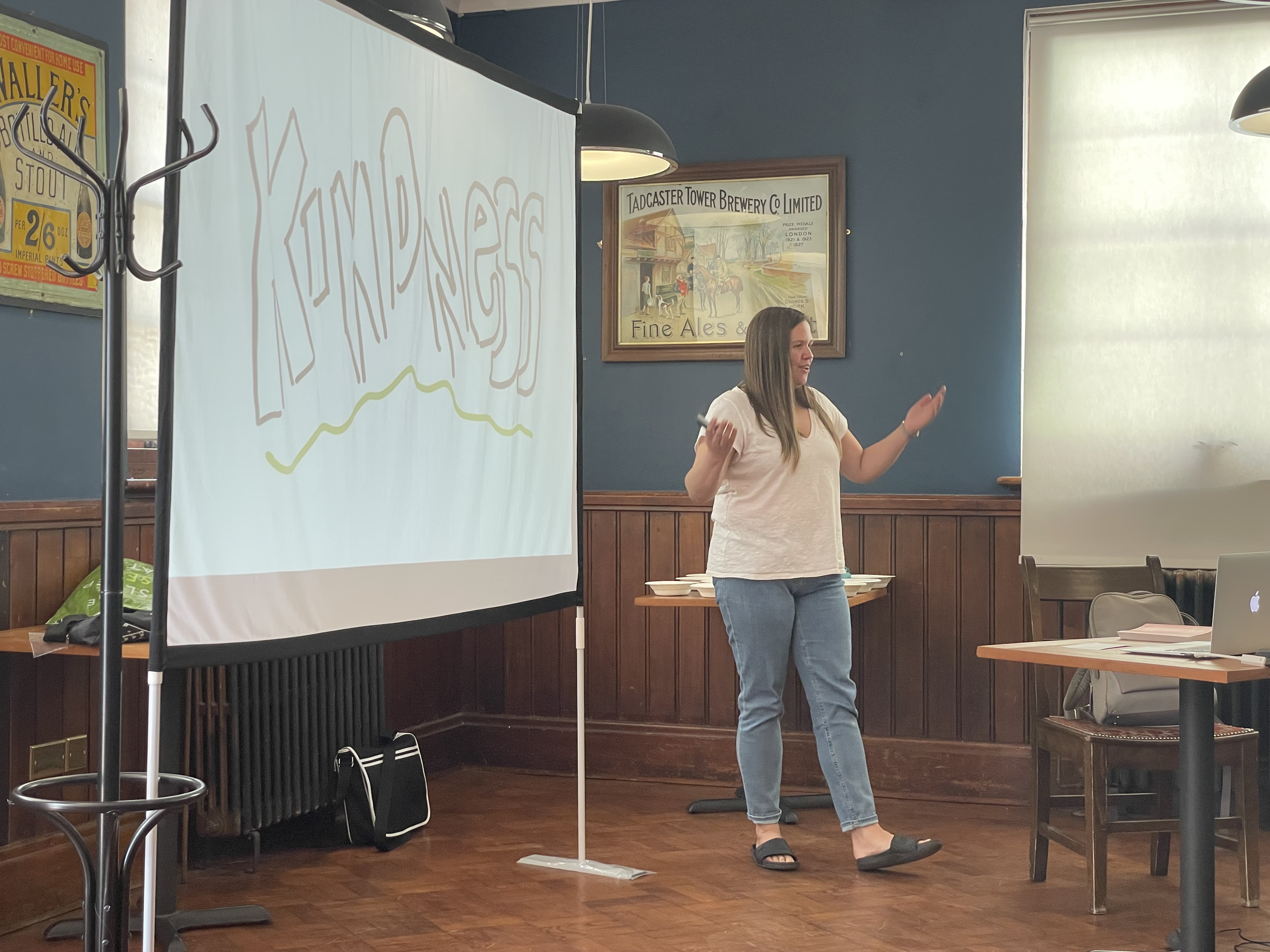 Lauren Borodajko speaking at Leeds Atelier, there is a slide in the background that says 'kindeness'