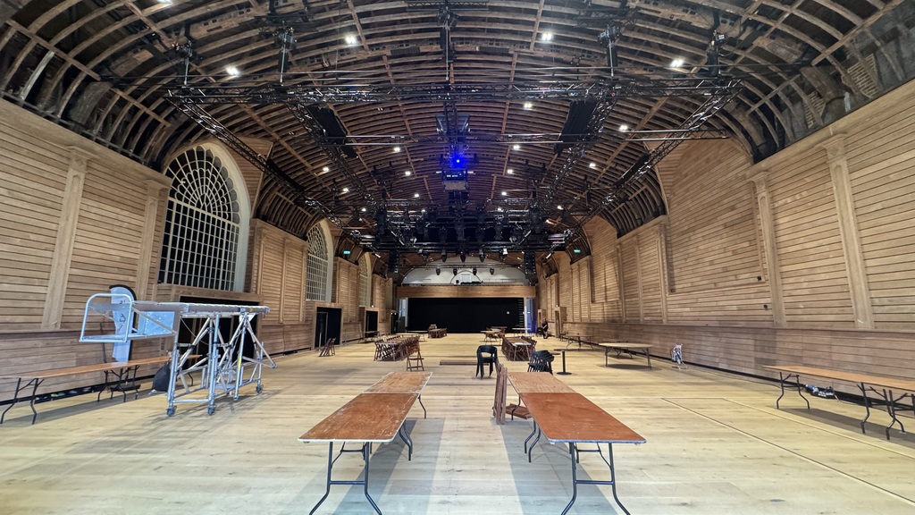Photo of an empty large hall. Generic ugly brown tables, some table cloths, a general level of disarray.  image