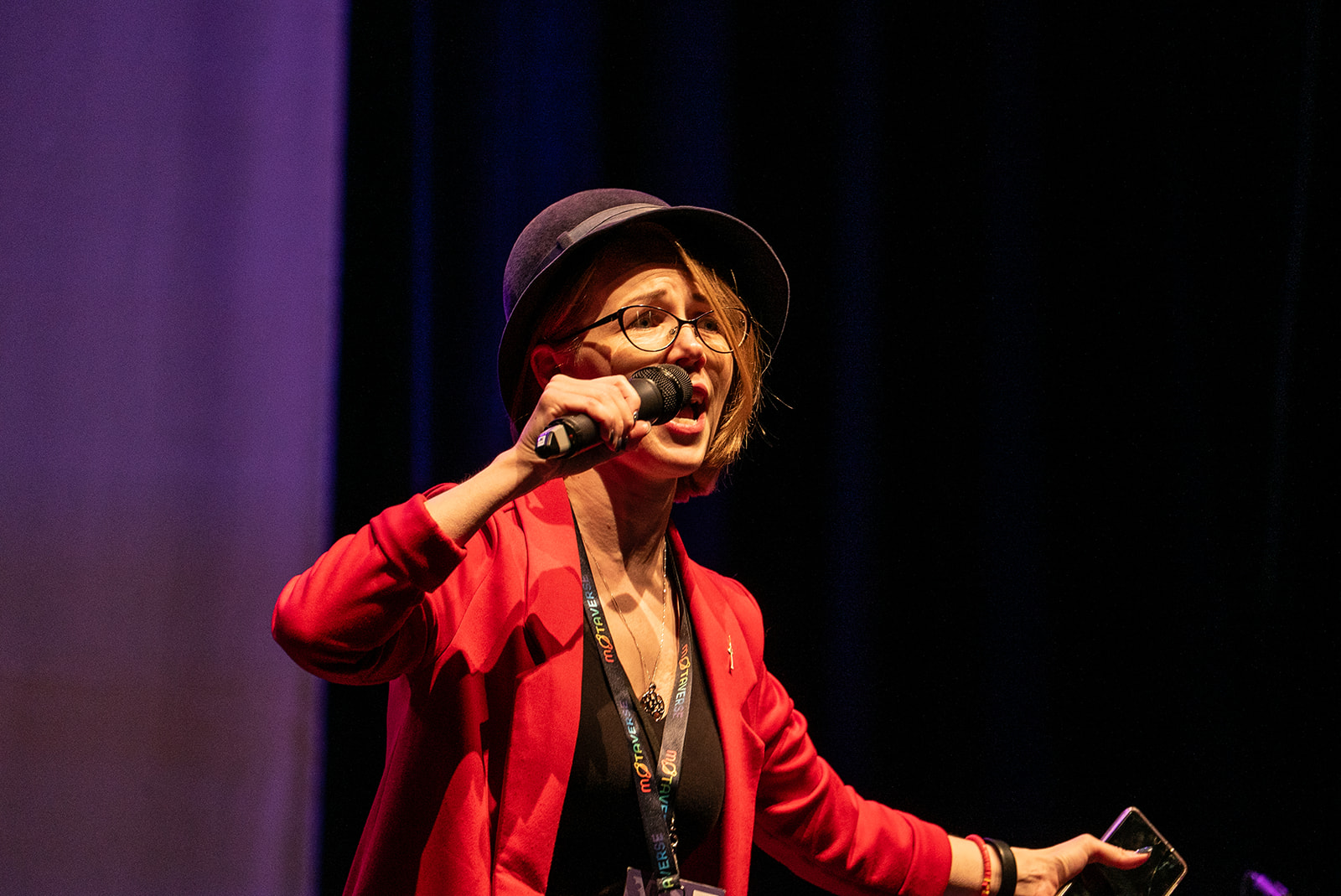 Christine Pinto, dressed in red, holding a mic like she is singing on the MoTaCon stage.
