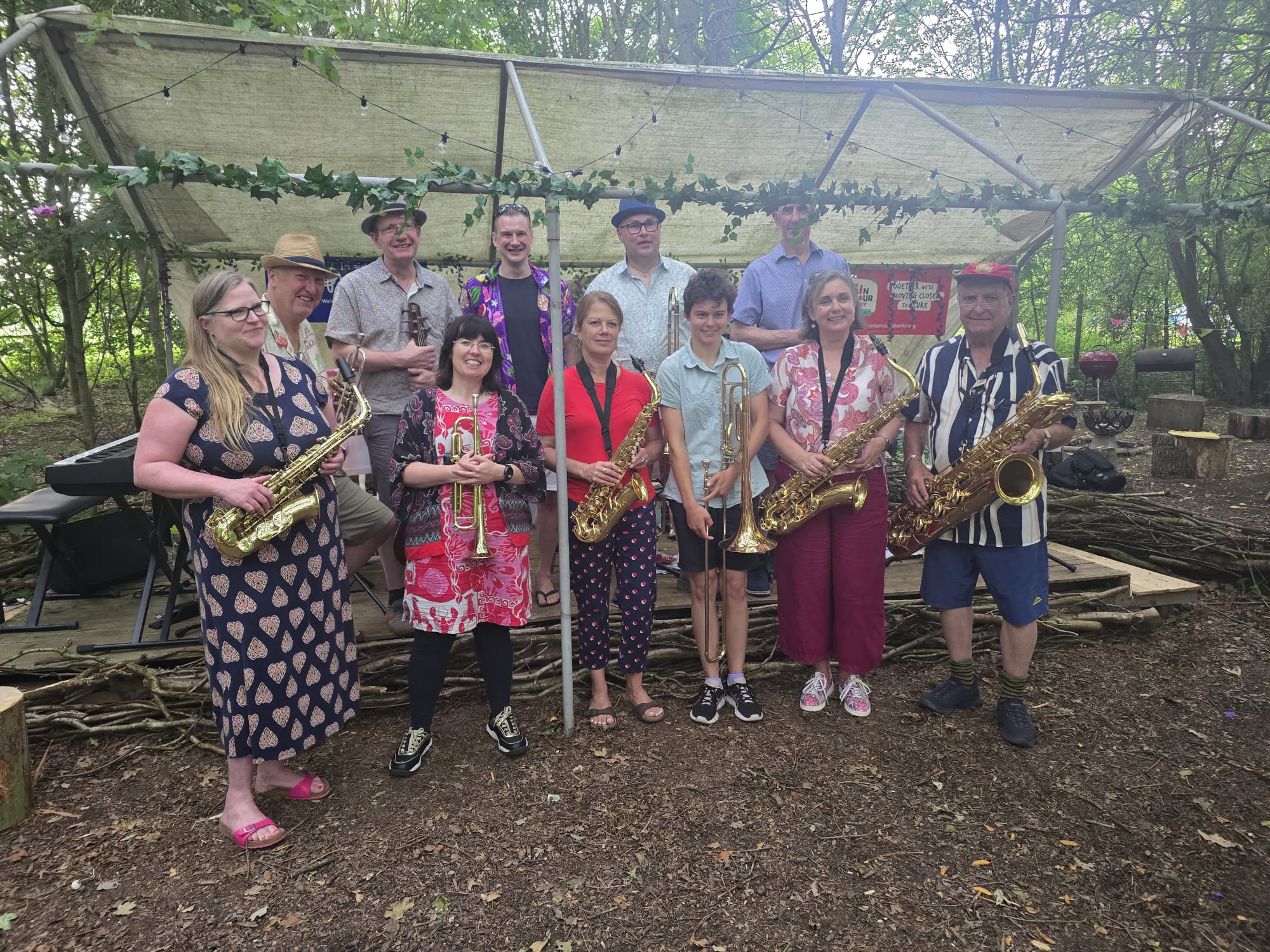 Picture of Jazz Band standing at the front of a makeshift stage in the middle of a forest. image