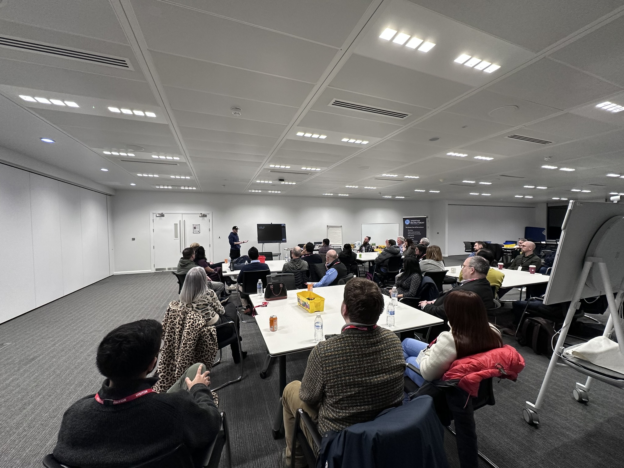 Room of attendees on tables listening to a speaker