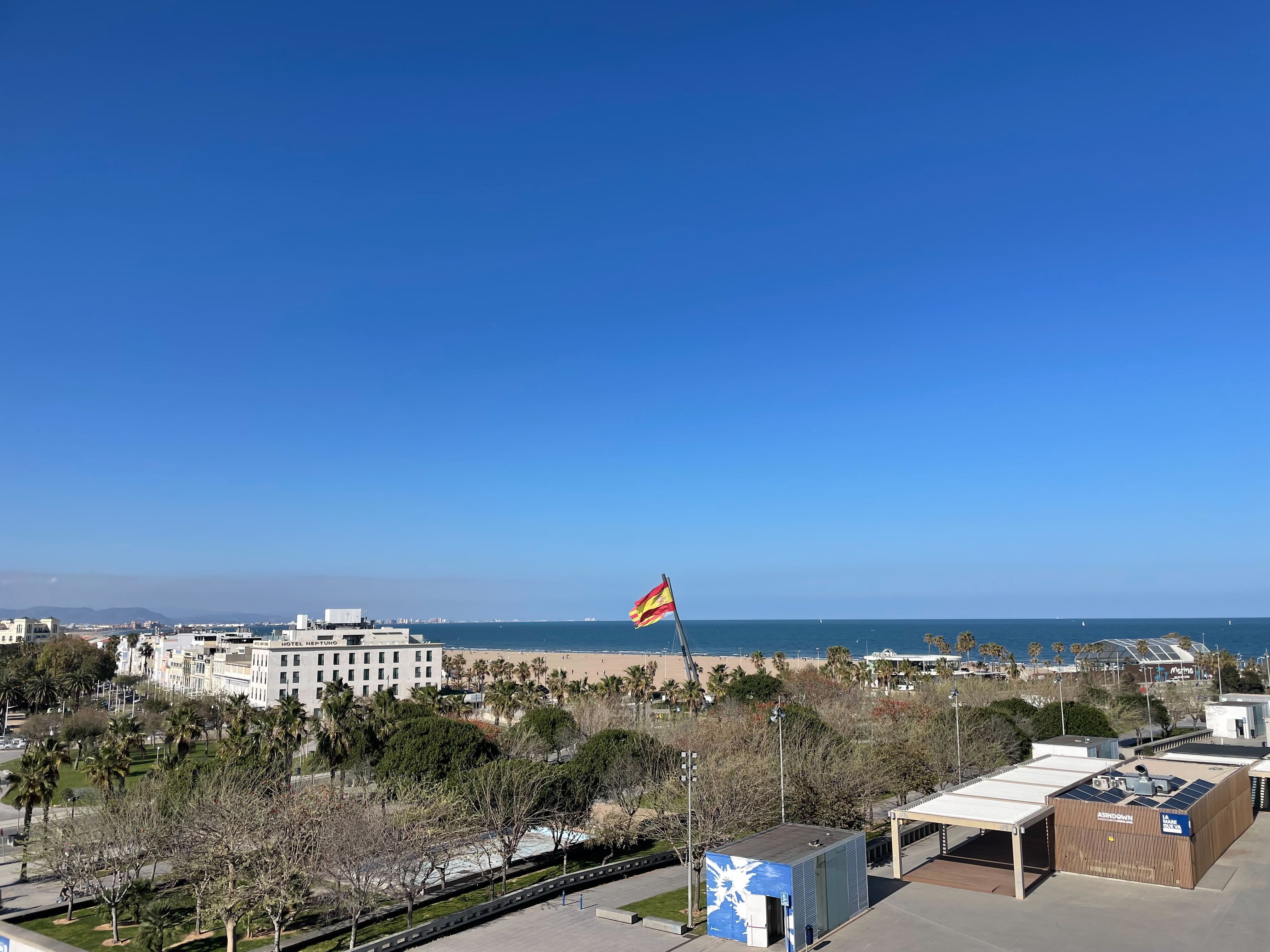 Photo of the beach, blue skies and a couple of flags.