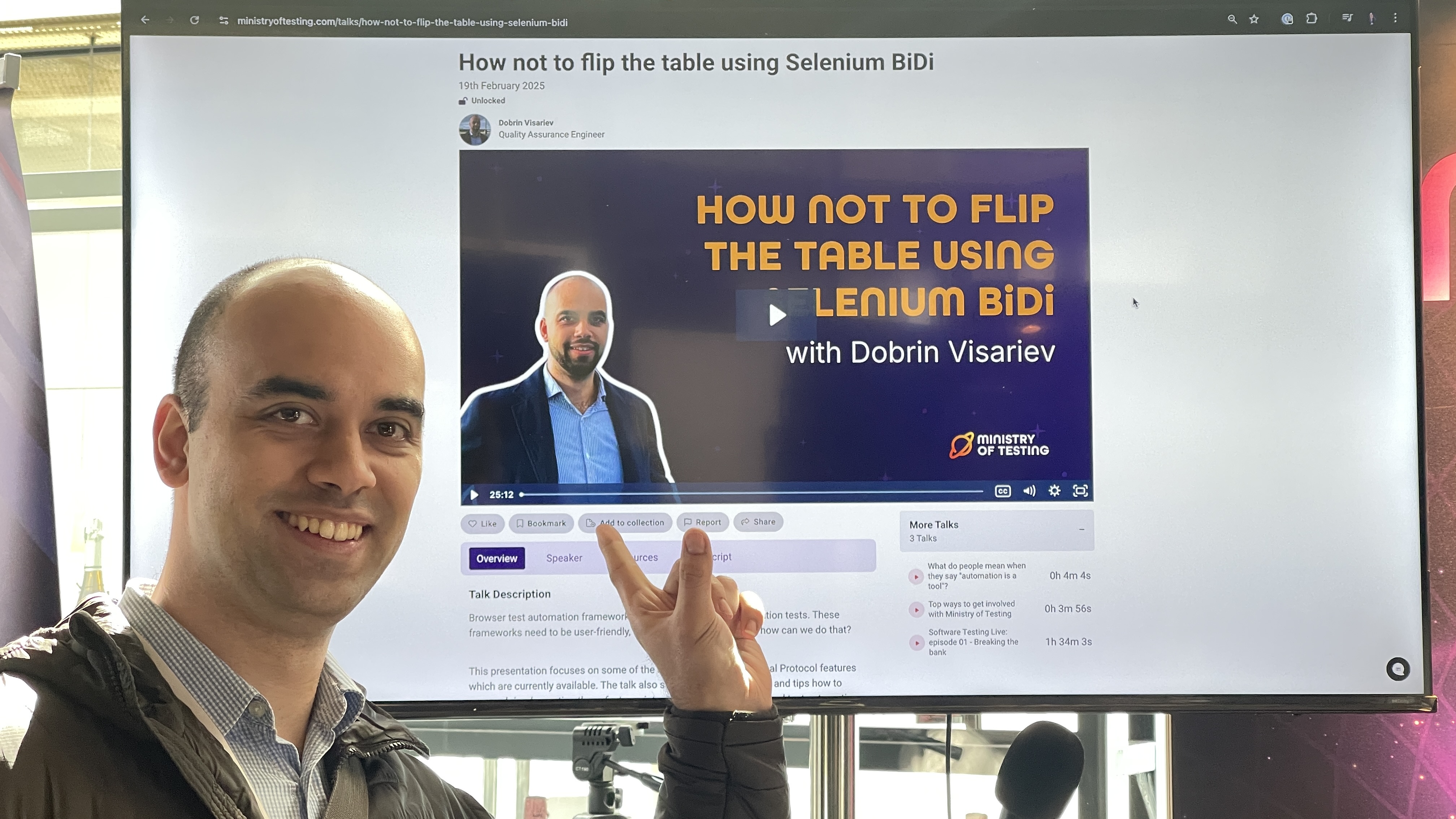 Dobrin Visariev smiles and points to a screen at the Ministry of Testing stand displaying his talk titled “How Not to Flip the Table Using Selenium BiDi” — one of the contributions in the MoTaverse.