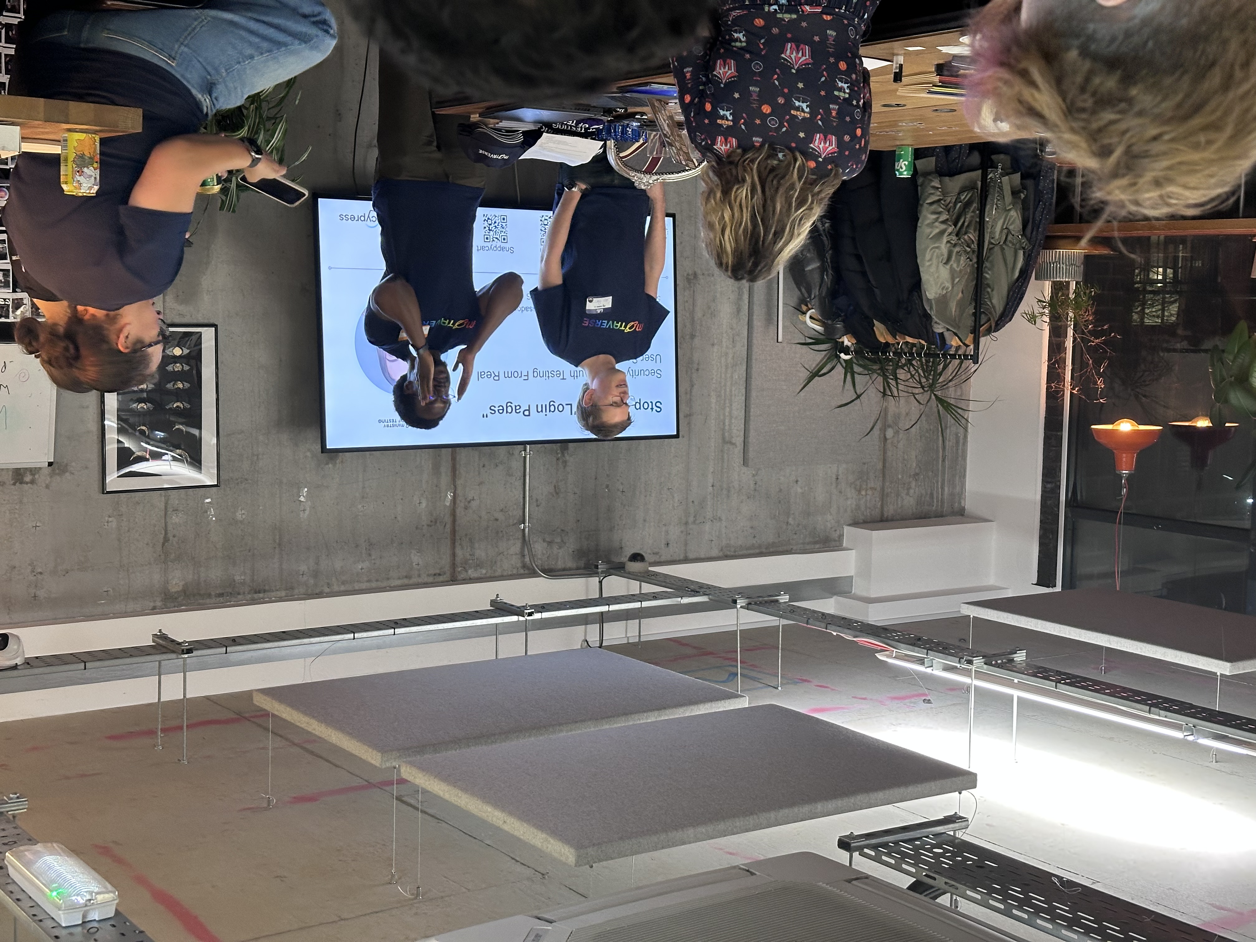 Two men standing at the front in a MoTaVerse blue T-shirts addressing a room.