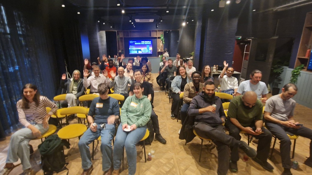 A diverse group of audience members seated in rows of yellow and black chairs inside a modern presentation room, with... image
