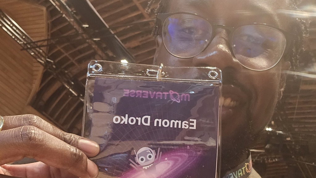 Selfie of black man with glasses holding name badge that reads "Eamon Droko". The image is mirrored so his name is writted backwards.

