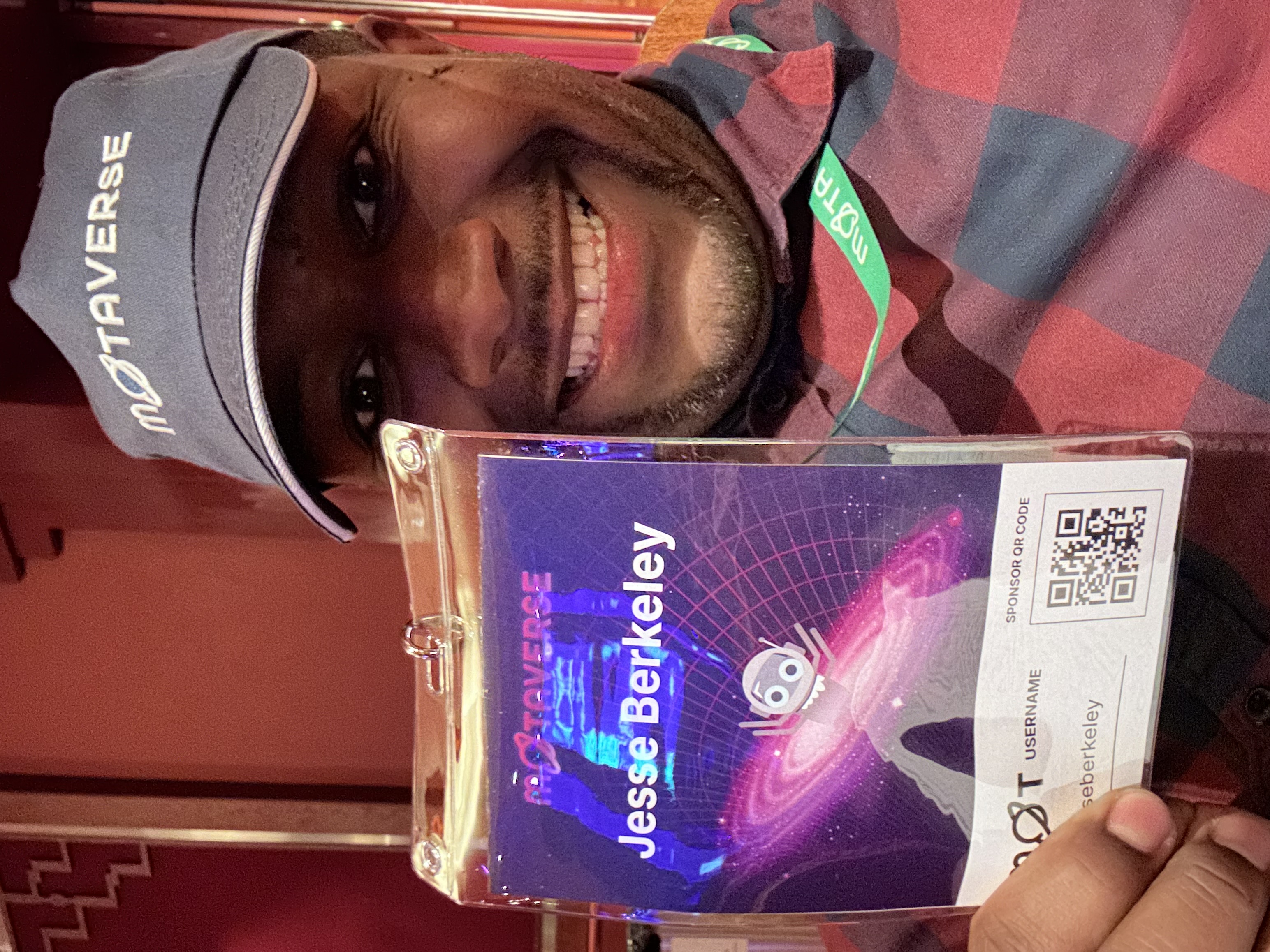 A selfie of a man holding a conference pass with his name on it.