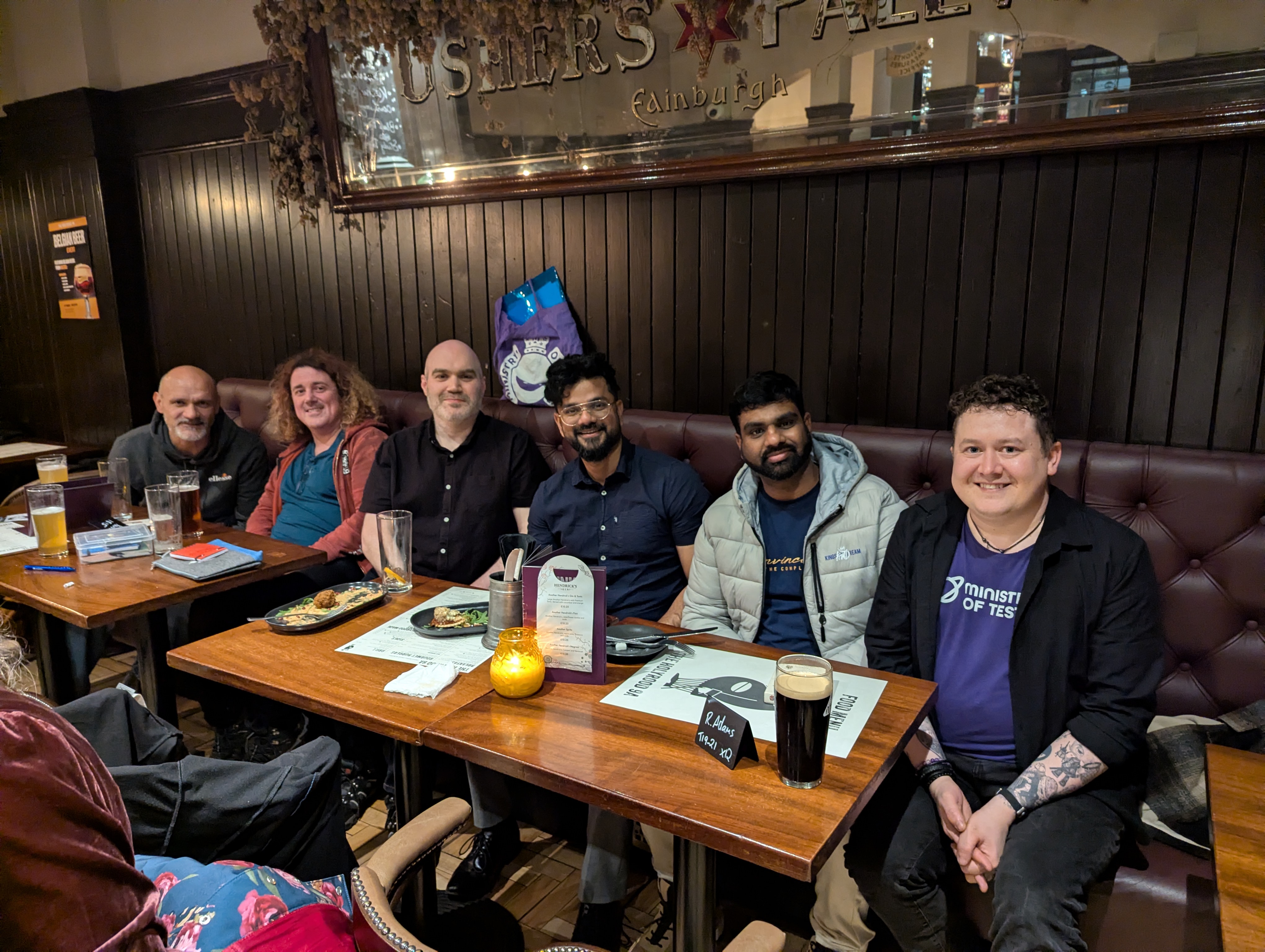 6 people spread in a row in a pub with smiling faces. image