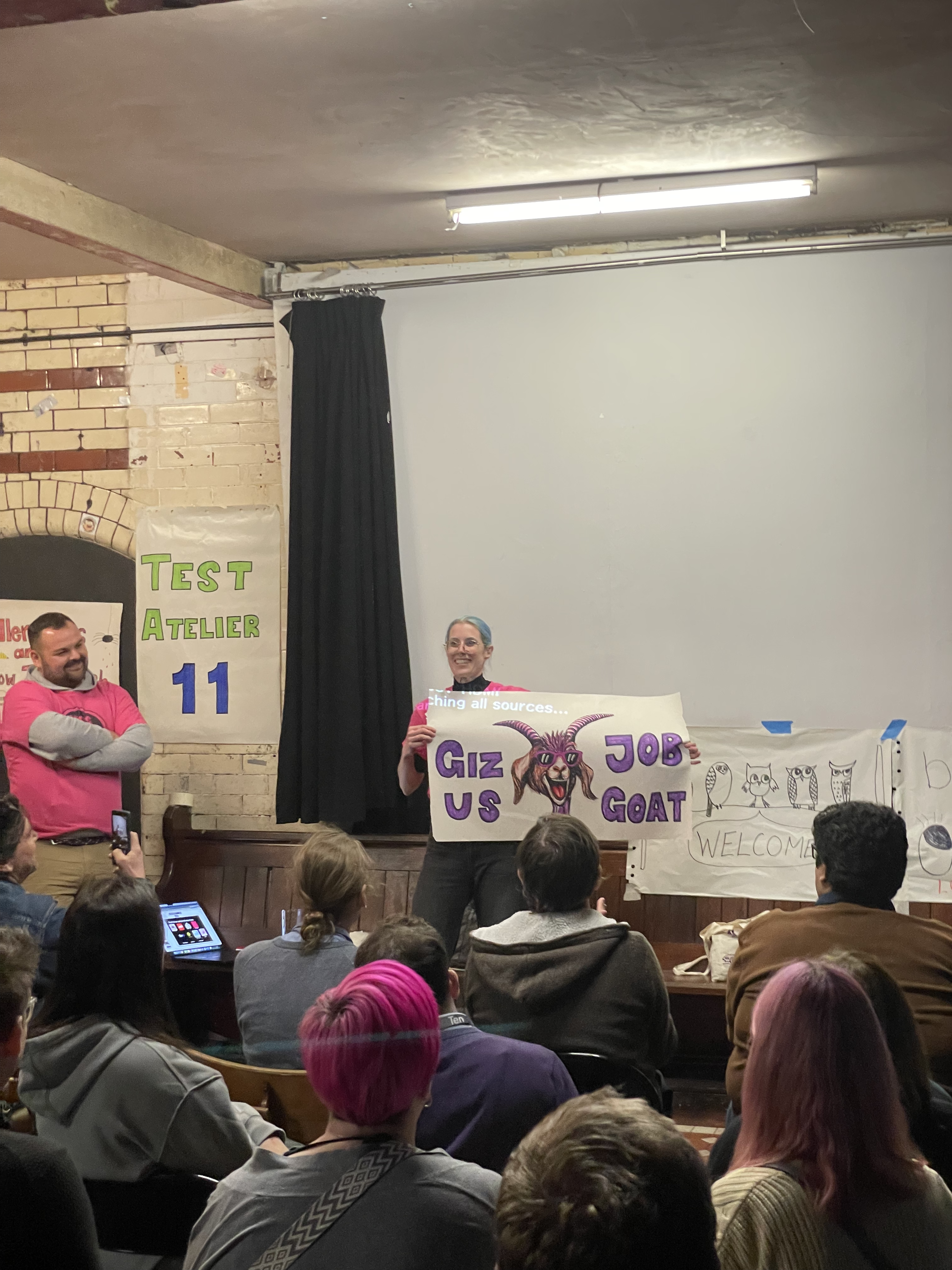 Gwen holding up a hand drawn poster with a goat that says 'giz us job goat' image