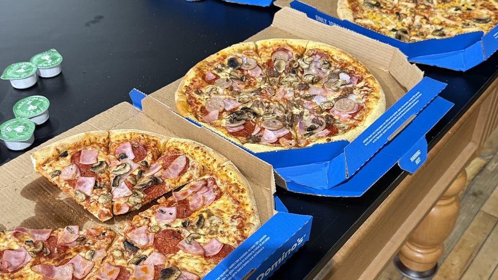 Open boxes of pizza on a table with 5 different kinds  image