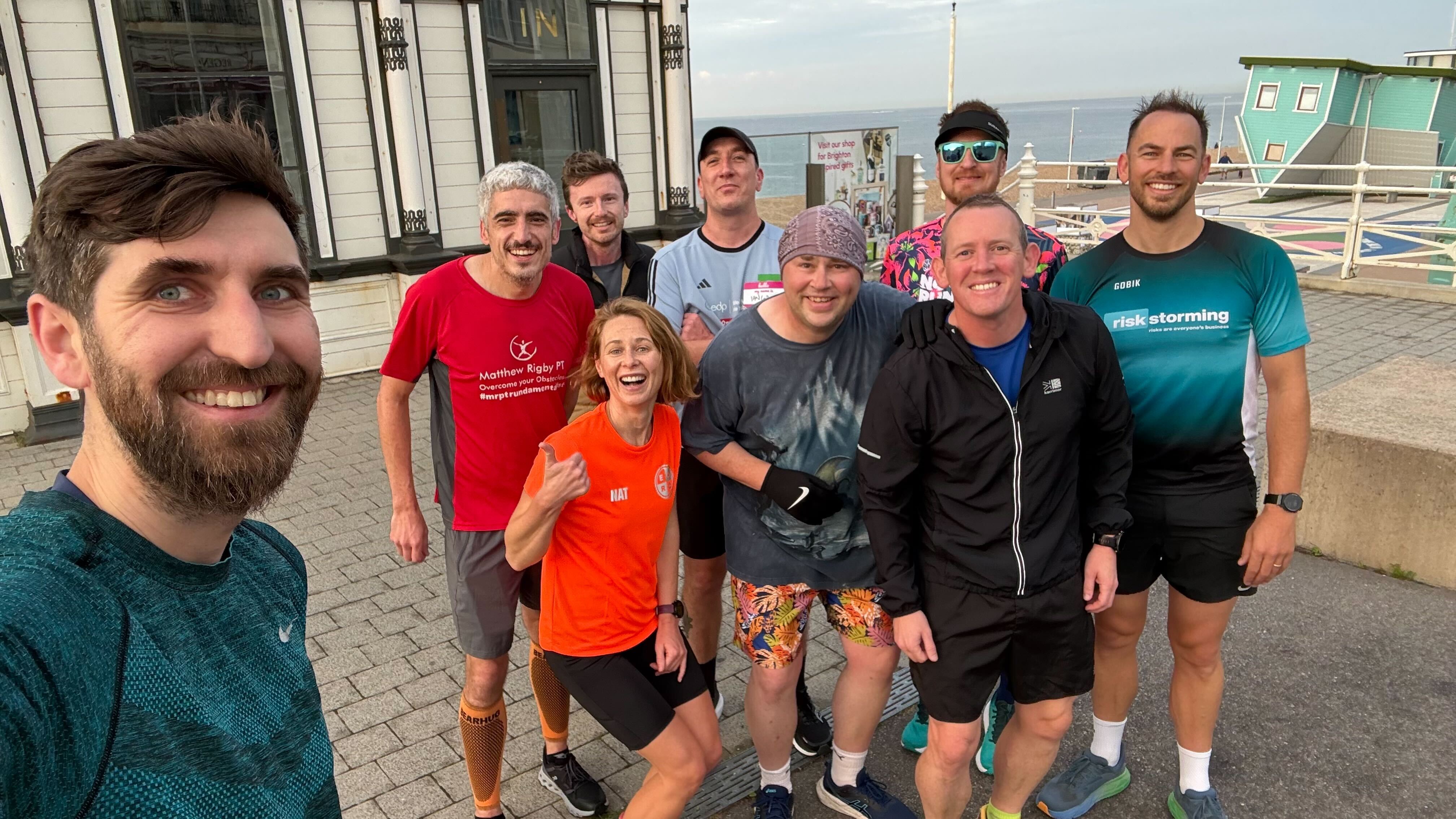 A group of people, testing professionals, wearing running kits and posing for photo next to Brighton i360.